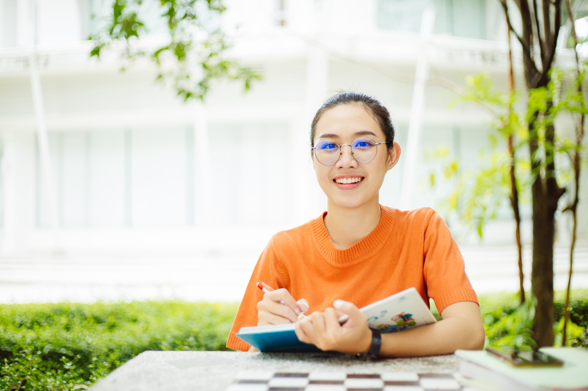 Portrait of nerd Asian woman girl smart teen happy smiling with glasses at green park outdoor in uni